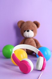 Photo of Baby songs. Headphones, balls and toy bear on violet background