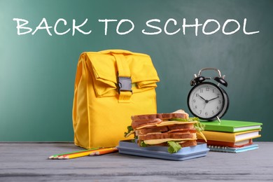 Image of Composition with lunch box and food on table near blackboard