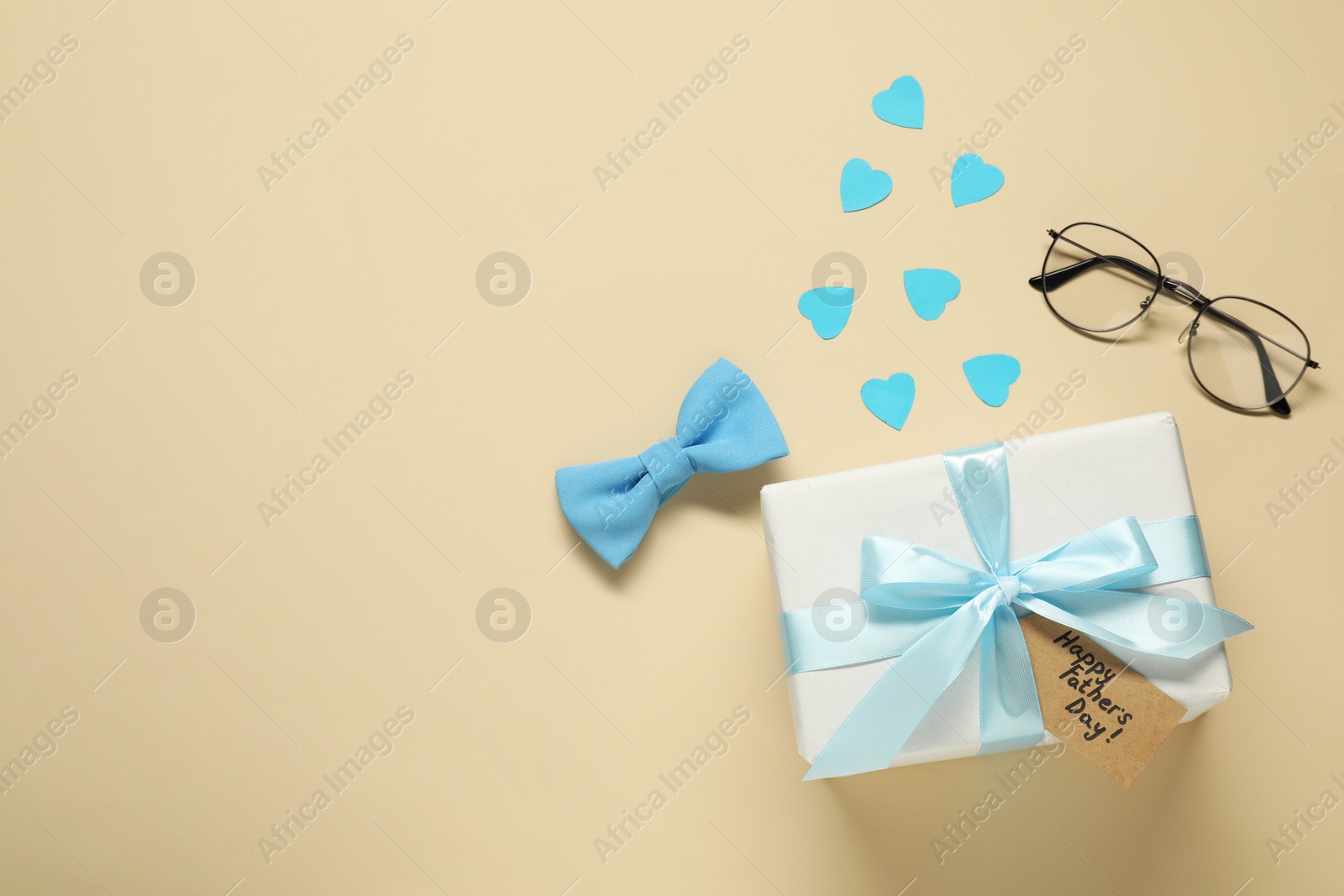 Photo of Card with phrase Happy Father's Day, gift box, paper hearts and men accessories on beige background, top view. Space for text