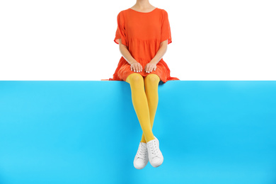 Photo of Woman wearing yellow tights and stylish shoes sitting on color background, closeup