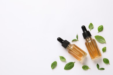 Photo of Bottles of essential basil oil and fresh leaves on white background, flat lay. Space for text