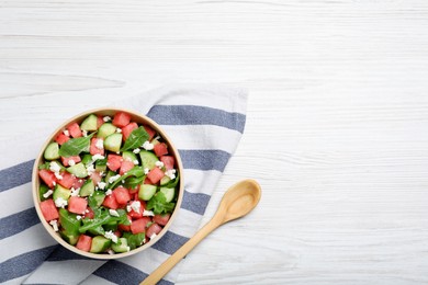 Photo of Delicious salad with watermelon, cucumber, arugula and feta cheese on white wooden table, flat lay. Space for text