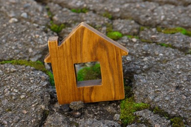 Photo of Wooden house model in cracked asphalt. Earthquake disaster