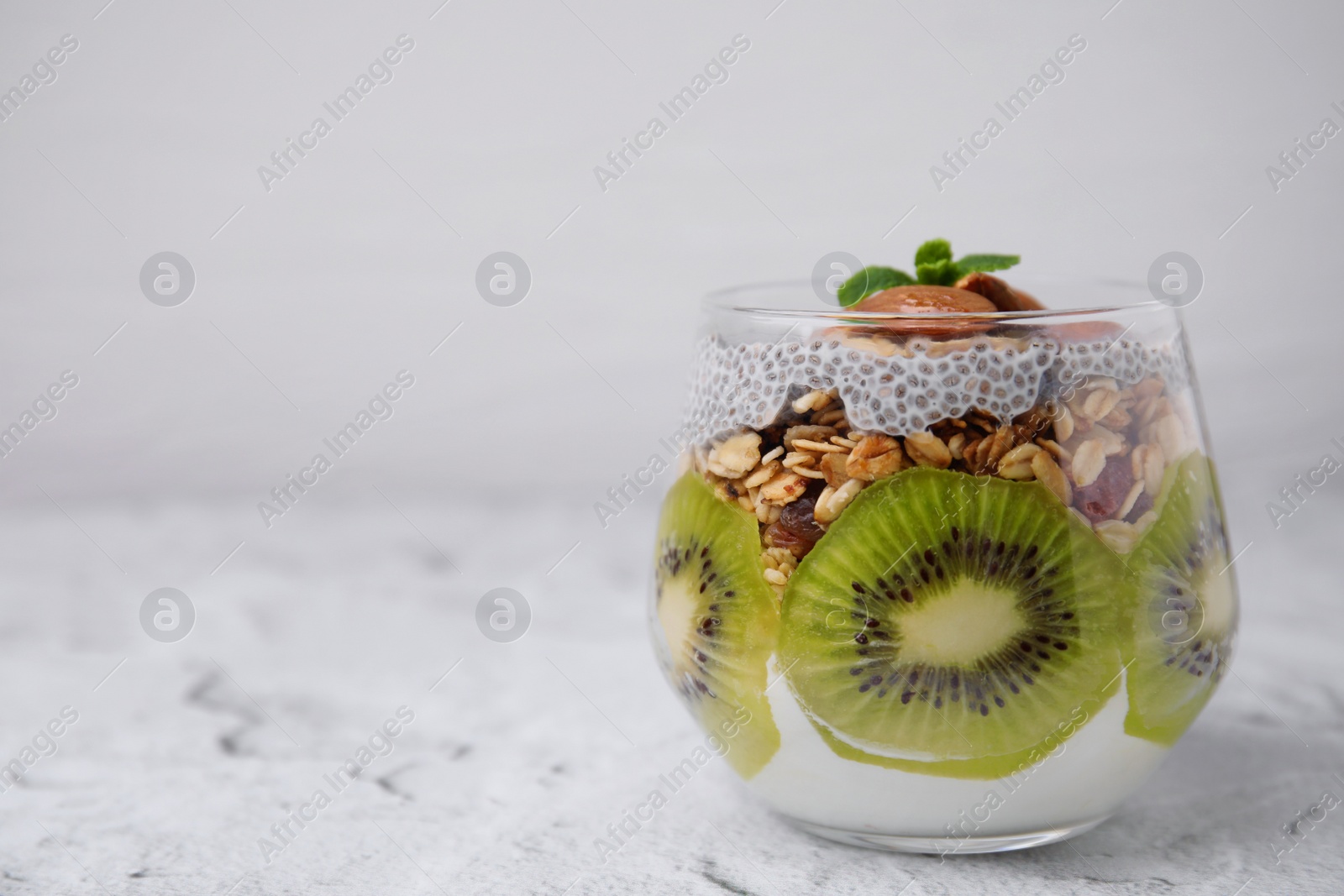 Photo of Delicious dessert with kiwi, chia seeds and almonds on light textured table, space for text