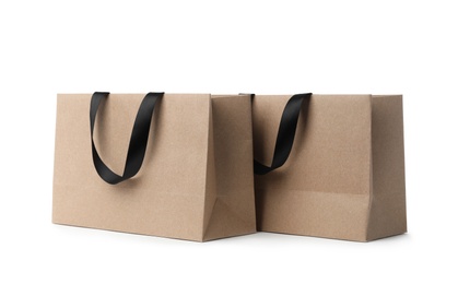 Photo of Paper shopping bags with ribbon handles on white background. Mockup for design