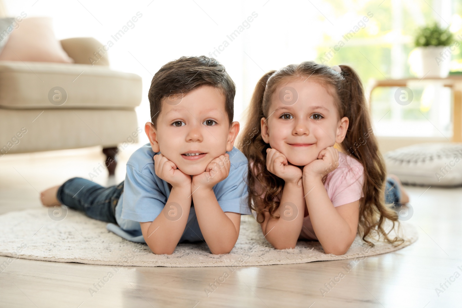 Photo of Cute children lying on carpet in living room