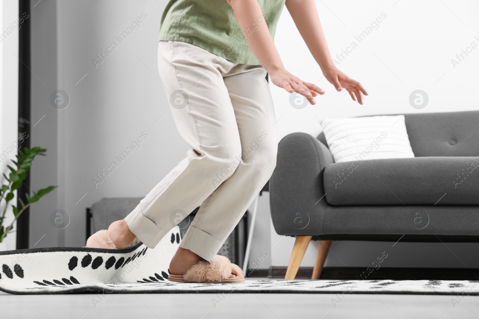 Photo of Woman tripping over carpet at home, closeup