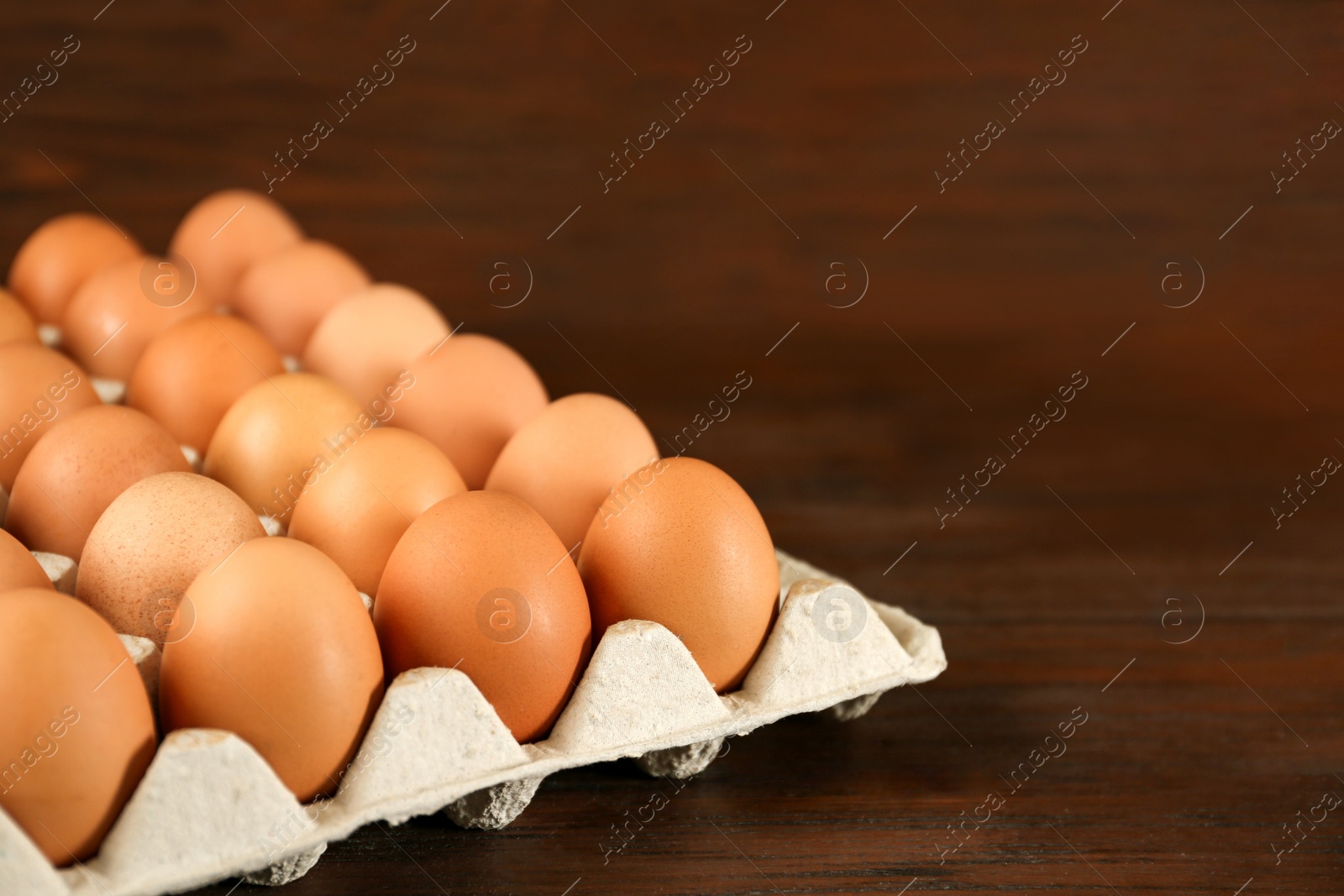 Photo of Raw chicken eggs in carton tray on wooden table