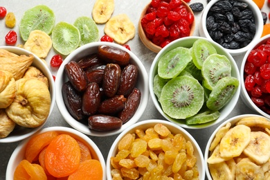 Bowls with different dried fruits on grey background, flat lay. Healthy food