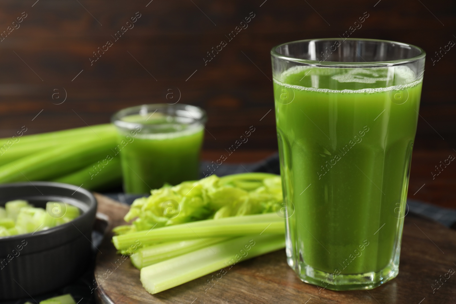 Photo of Glasses of delicious celery juice and vegetables on wooden board, closeup. Space for text