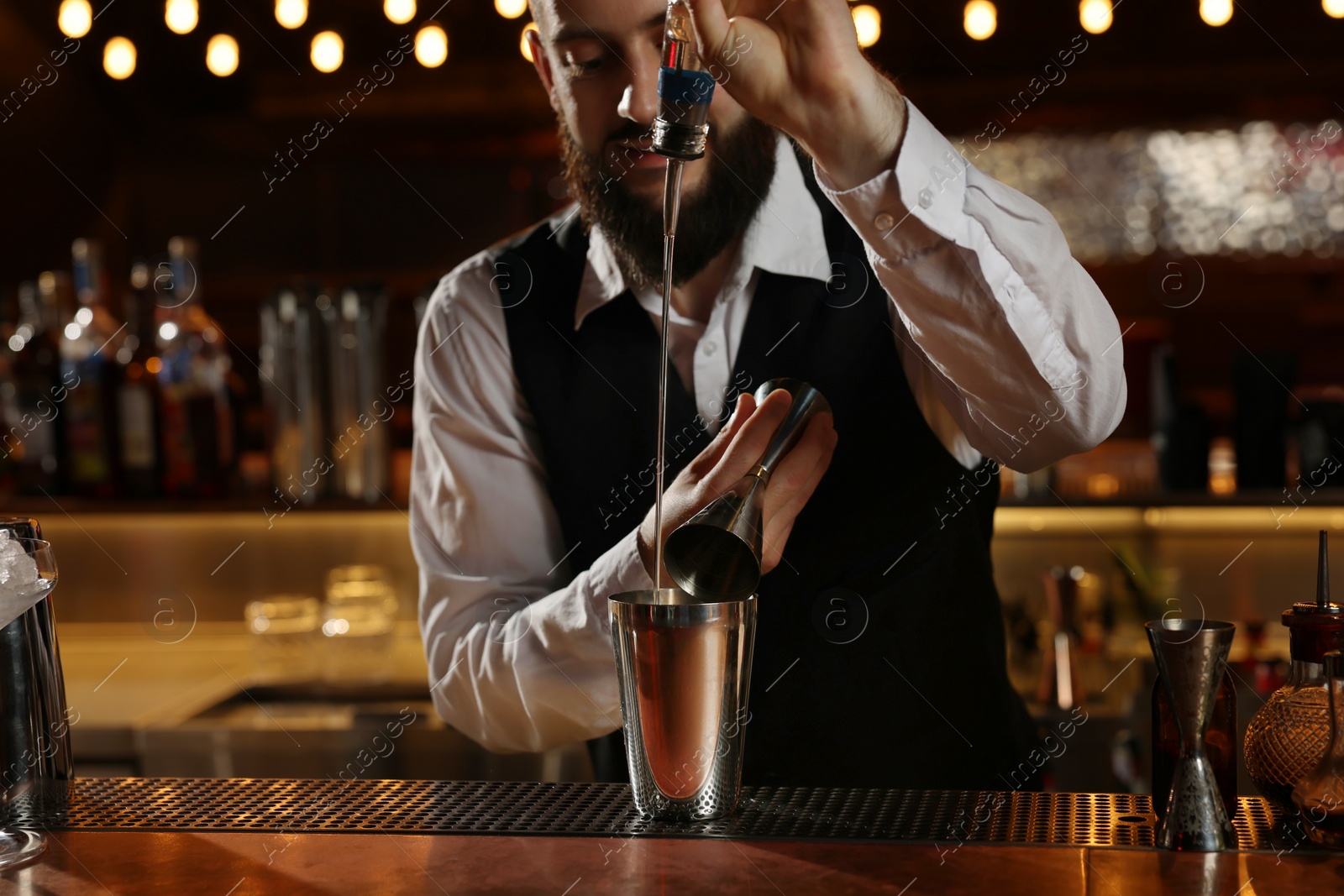 Photo of Bartender making fresh alcoholic cocktail at bar counter, selective focus