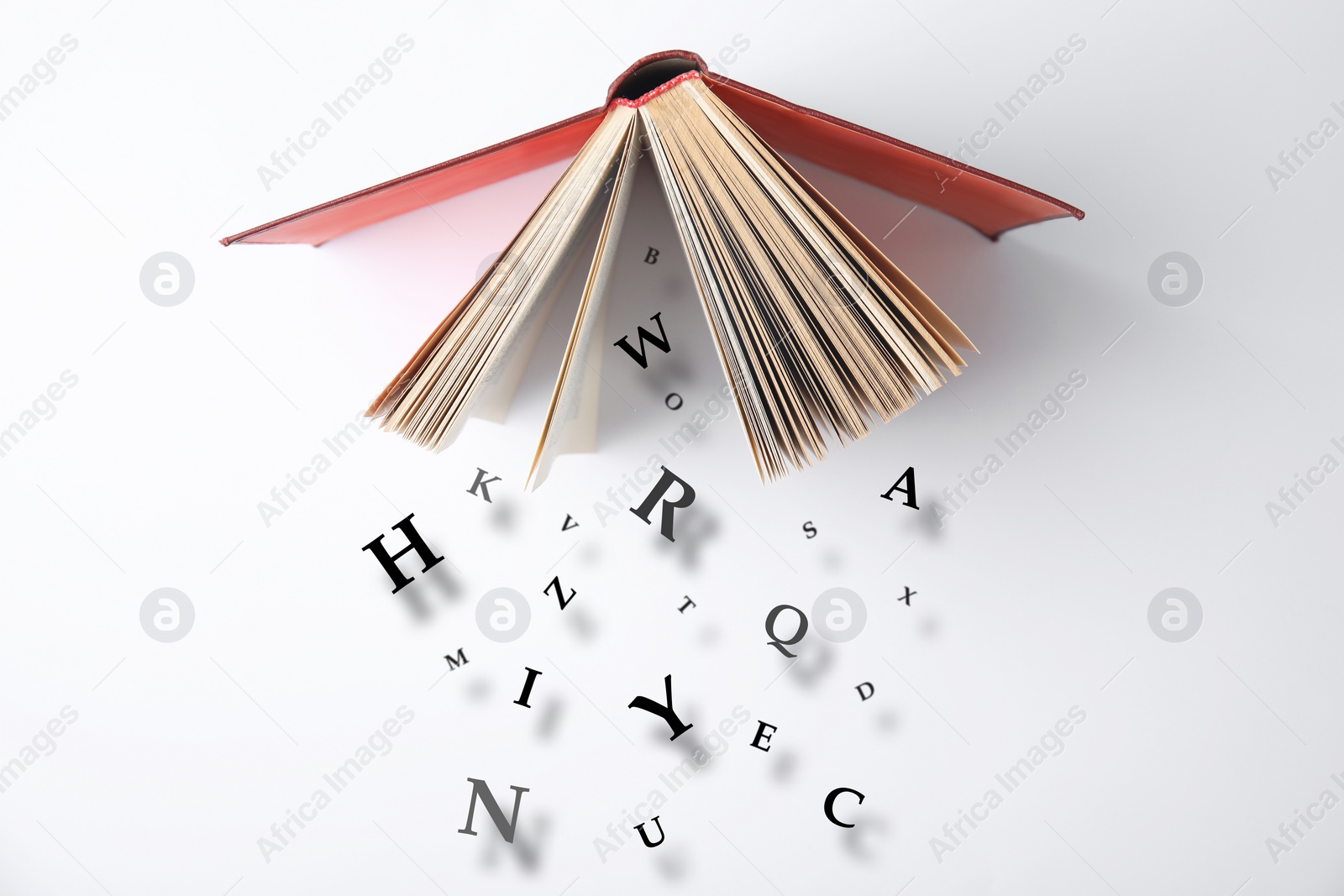 Image of Open book with letters falling out of it on white background