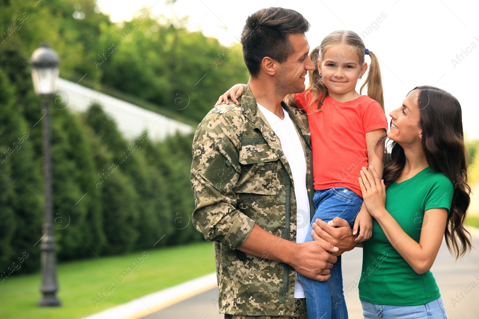 Photo of Man in military uniform with his family  at sunny park