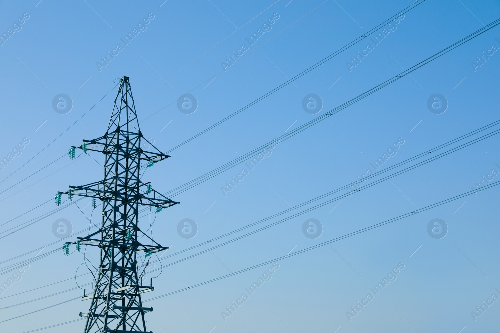 Photo of High voltage tower against blue sky on sunny day