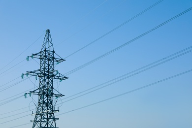 Photo of High voltage tower against blue sky on sunny day