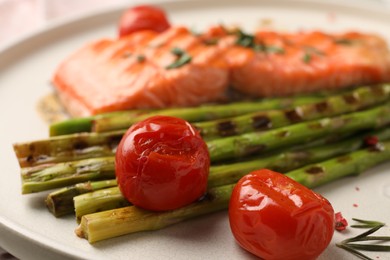 Photo of Tasty grilled asparagus, tomatoes and salmon on plate, closeup