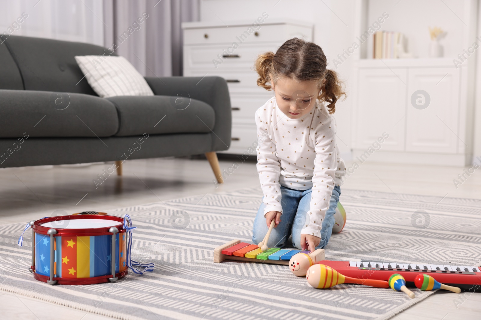 Photo of Little girl playing toy xylophone at home