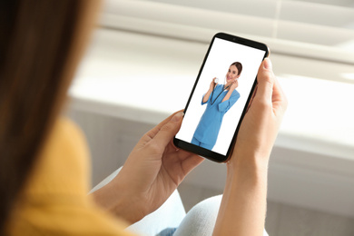Woman using smartphone for online consultation with doctor via video chat, closeup