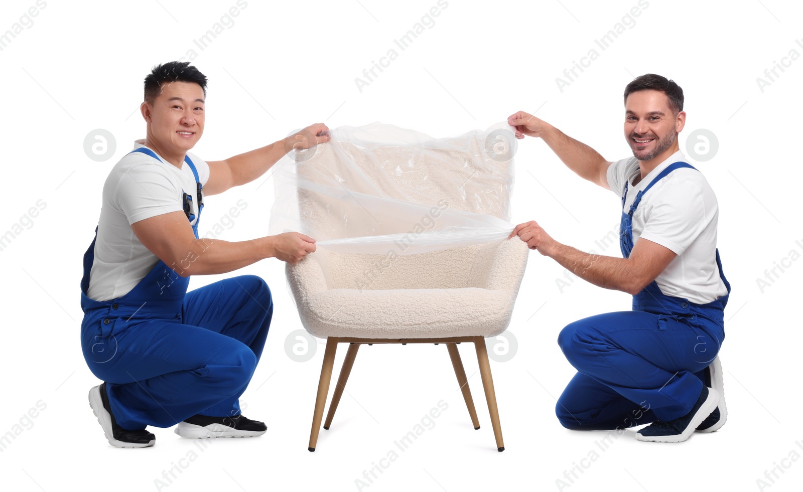 Photo of Workers covering armchair with plastic film on white background