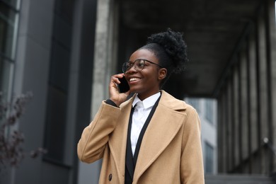 Photo of Happy woman talking on smartphone outdoors. Lawyer, businesswoman, accountant or manager