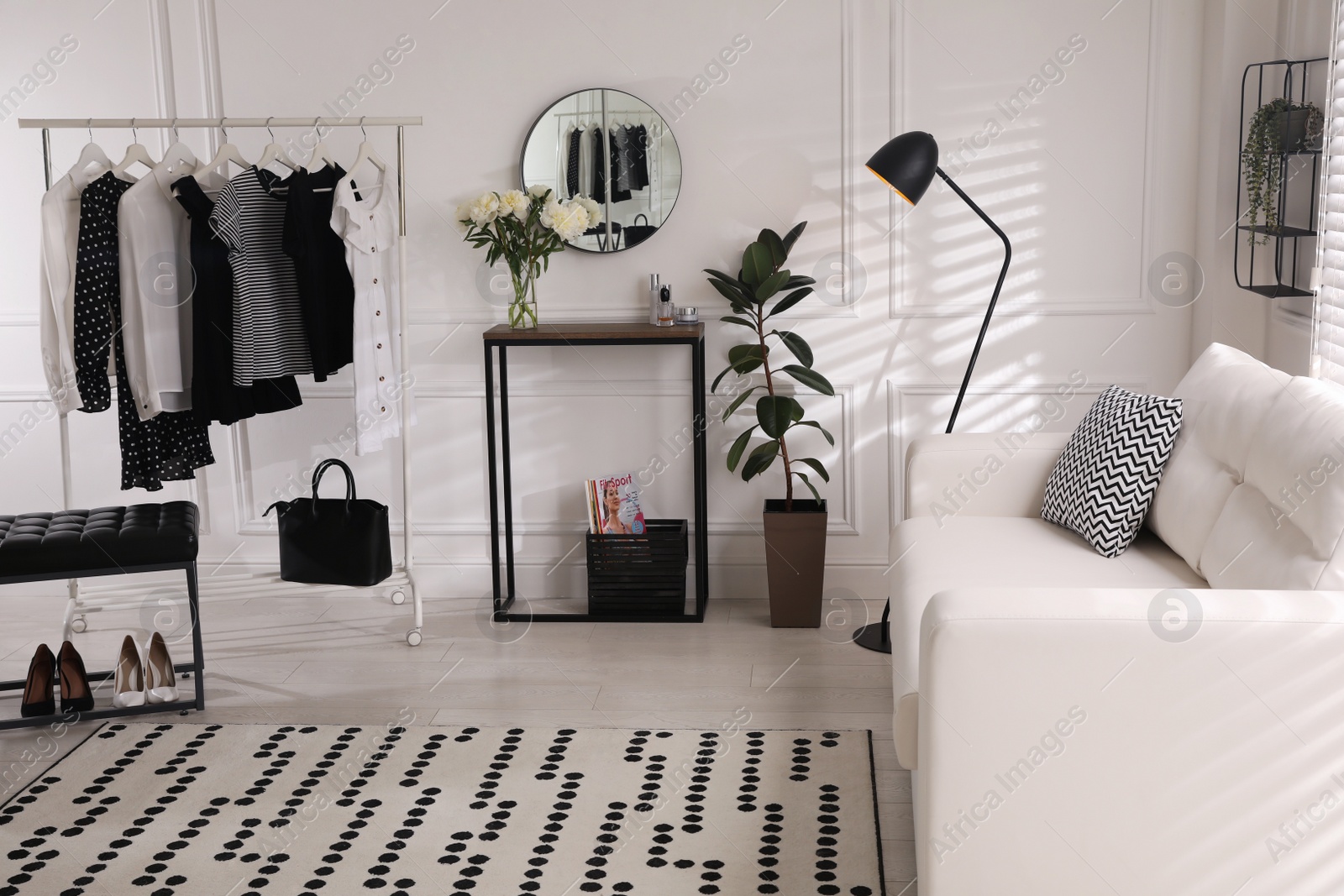 Photo of Rack with clothes near console table in room. Interior design