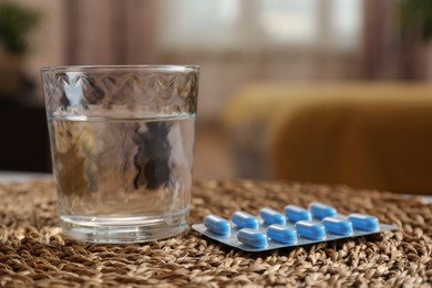 Photo of Glass of water and pills on wicker mat indoors, closeup with space for text. Potency problem concept