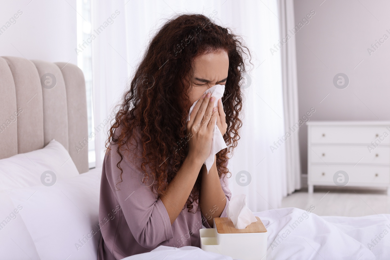 Photo of Sick African American woman with tissue in bed at home