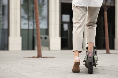 Photo of Businesswoman riding electric kick scooter on city street, closeup. Space for text