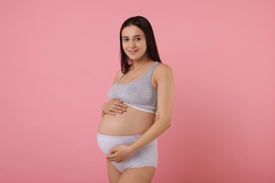 Beautiful pregnant woman in comfortable maternity underwear on pink background