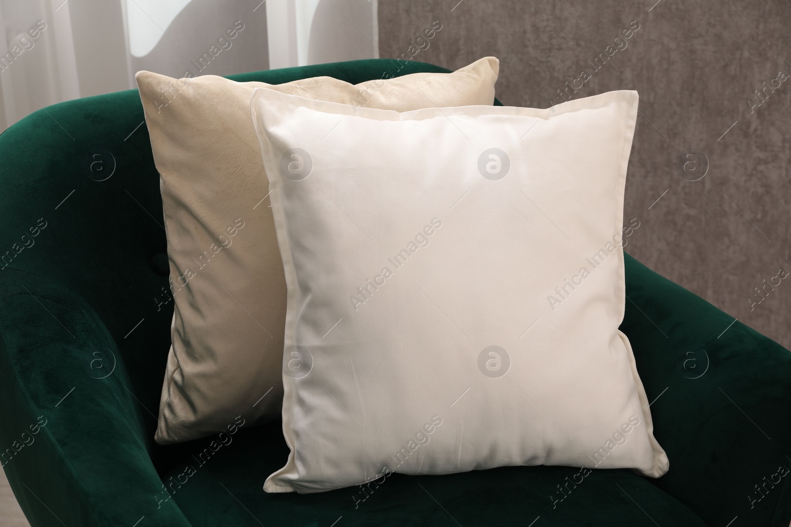 Photo of Soft pillows on green armchair in room