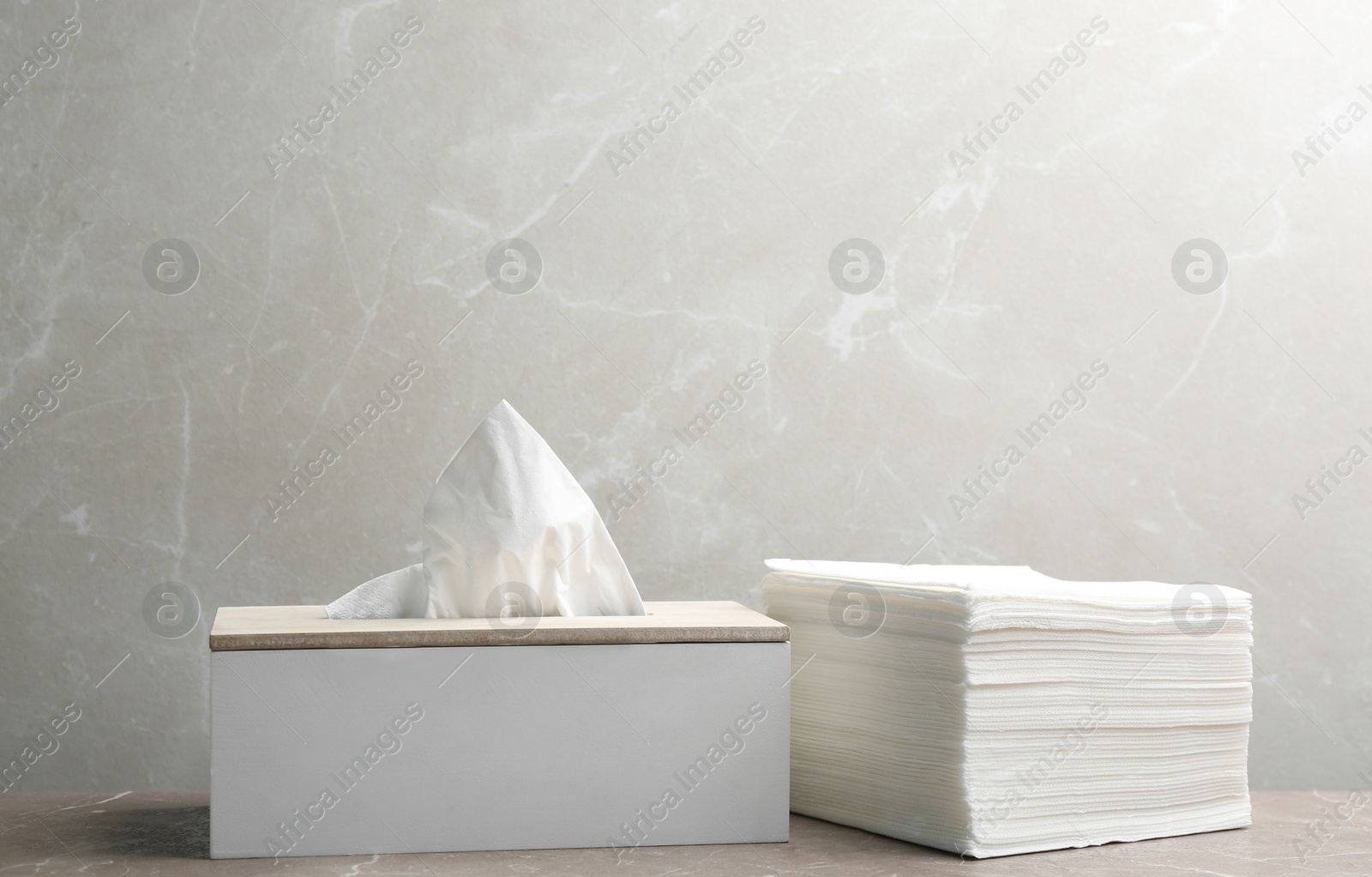 Photo of Box with tissues and stack of napkins on table