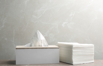 Box with tissues and stack of napkins on table