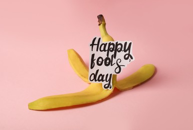Photo of Banana peel with words Happy Fool's Day on pink background