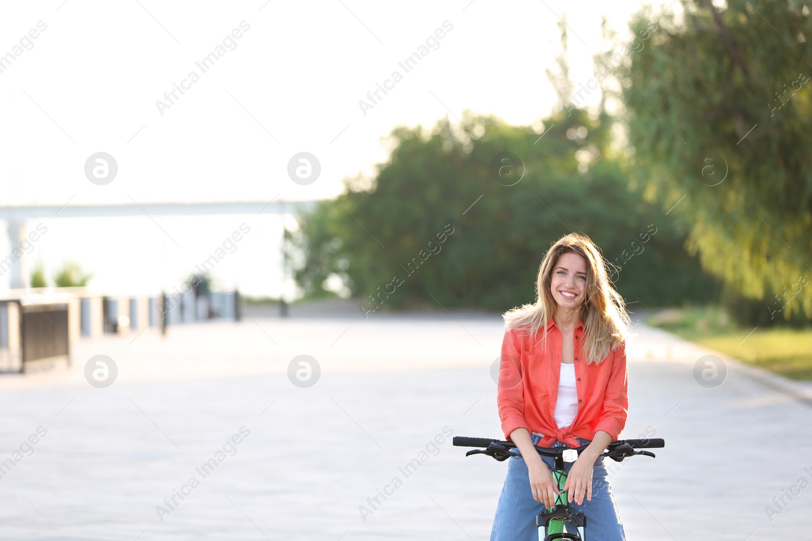 Photo of Young woman on modern bicycle in city. Space for text