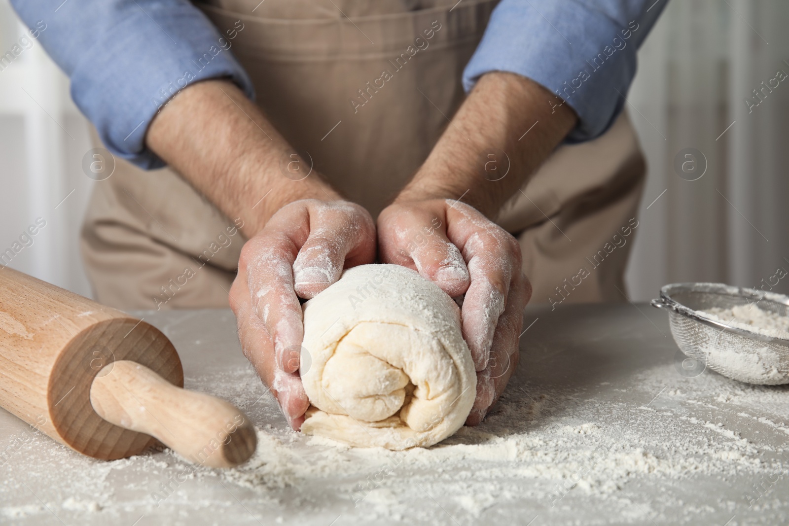 Photo of Man kneading dough for pastry on table