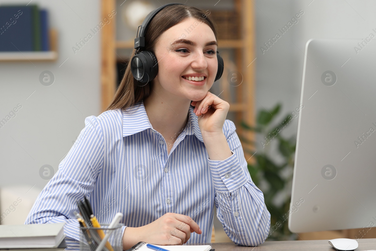 Photo of E-learning. Young woman using computer during online lesson at table indoors