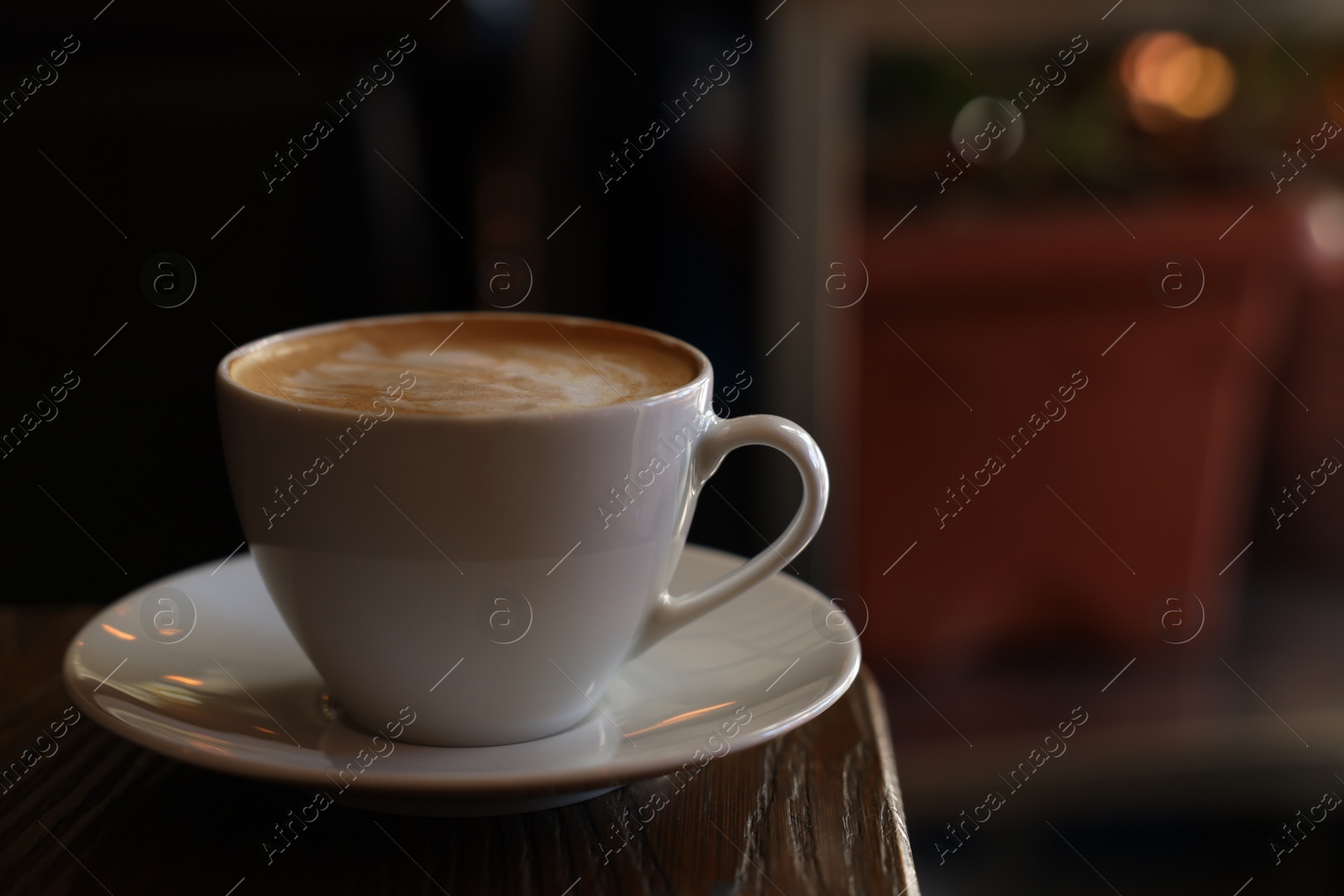 Photo of Cup of aromatic coffee with foam on table in cafe. Space for text