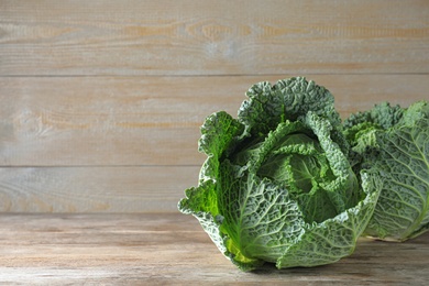 Photo of Fresh green savoy cabbages on wooden table. Space for text
