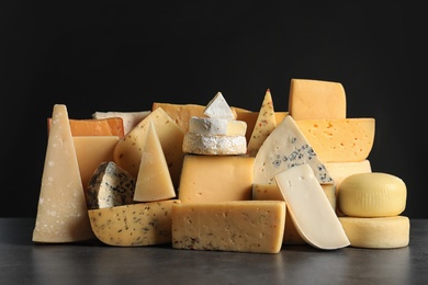 Different types of delicious cheese on table against black background