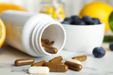 Photo of Bottle with vitamin pills on white marble table, closeup