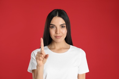 Woman showing number one with her hand on red background