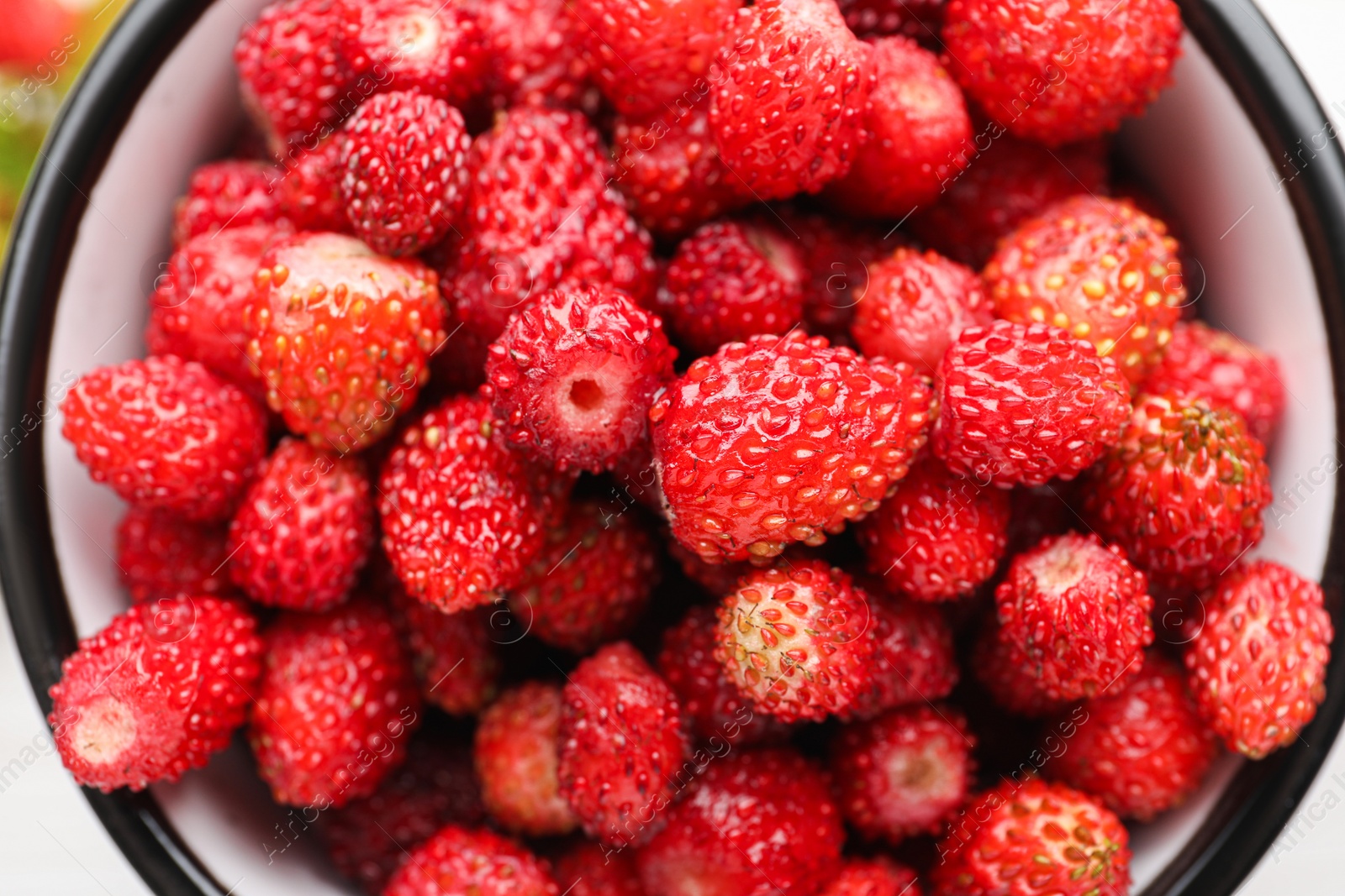 Photo of Fresh wild strawberries in mug, top view