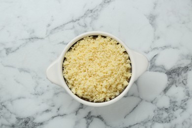 Photo of Bowl of tasty couscous on white marble table, top view