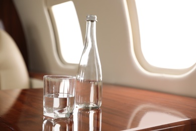 Image of Glass and bottle with water on plane. Comfortable flight