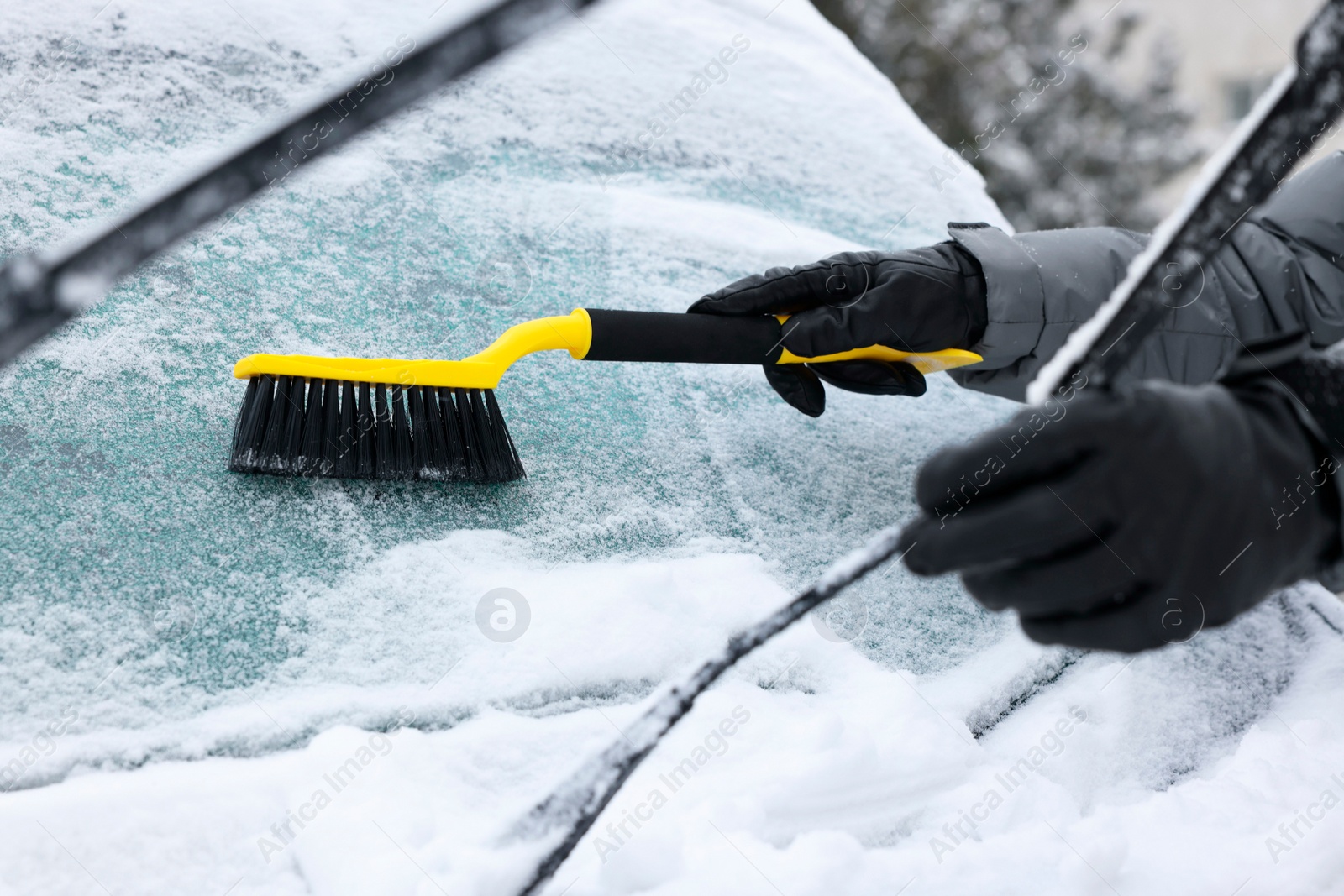 Photo of Man cleaning snow from car windshield outdoors, closeup