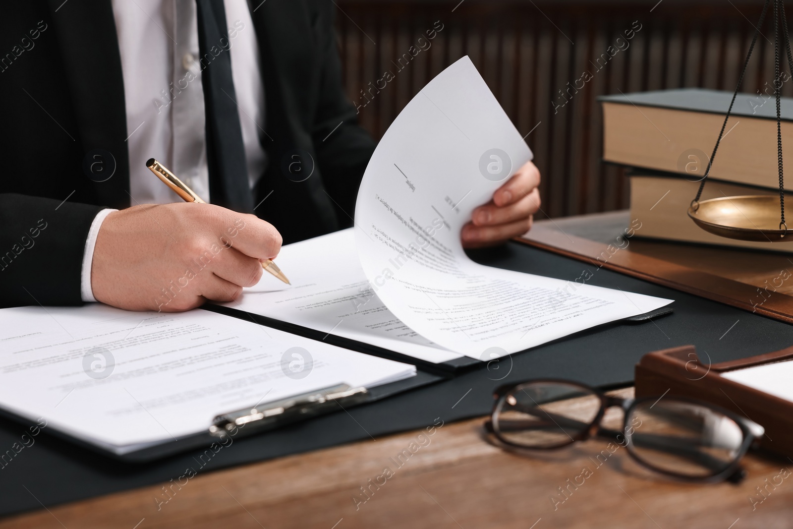 Photo of Lawyer working with documents at wooden table in office, closeup