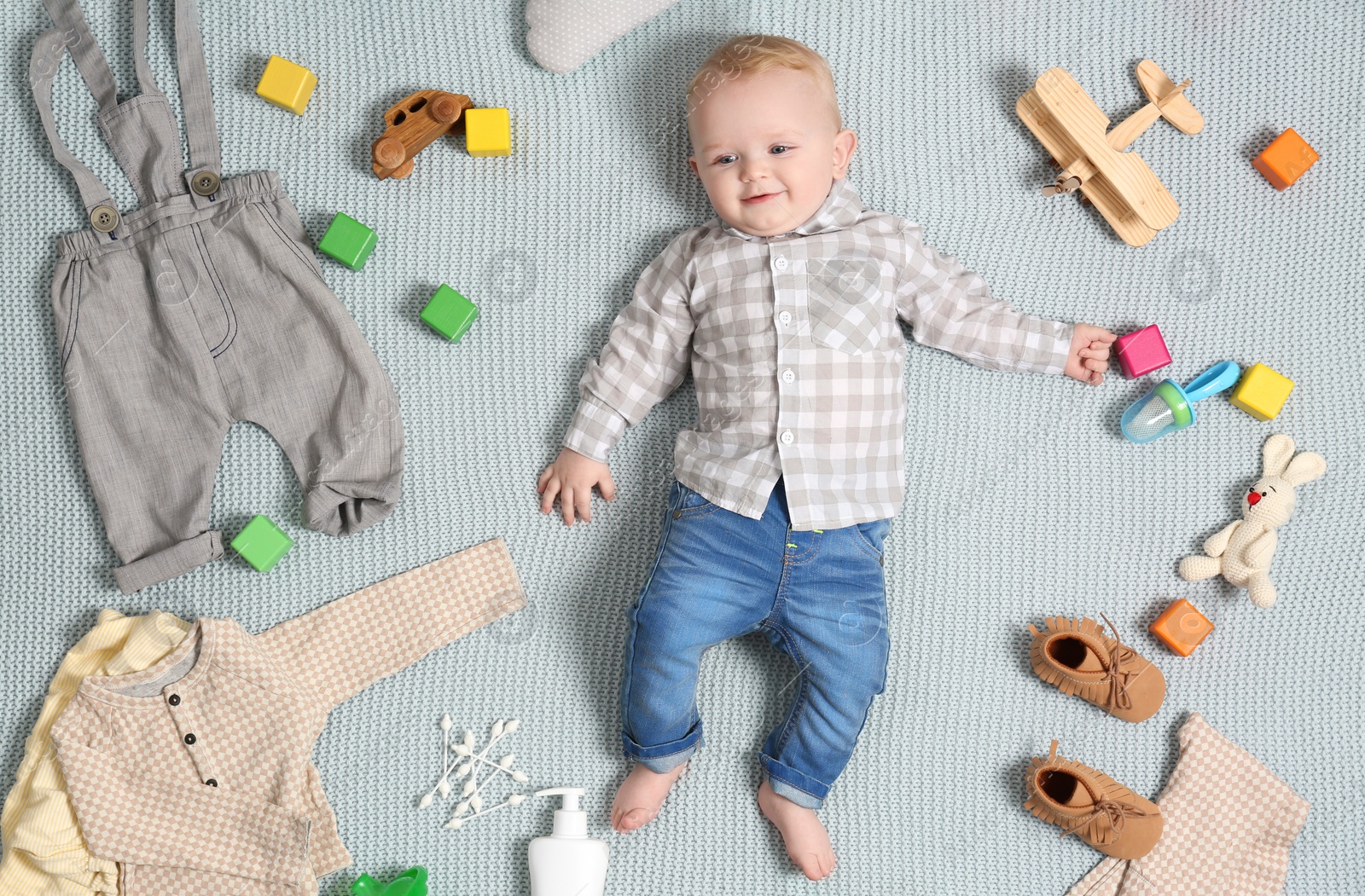 Photo of Cute little baby with clothing and accessories on color blanket, top view