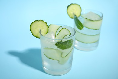 Tasty fresh cucumber water with mint on light blue background