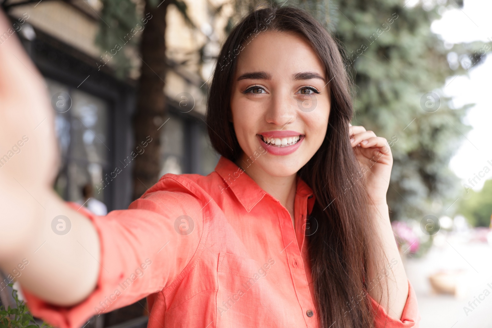 Photo of Beautiful young woman taking selfie outdoors on sunny day