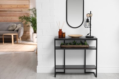 Console table with decor near mirror in room. Interior design